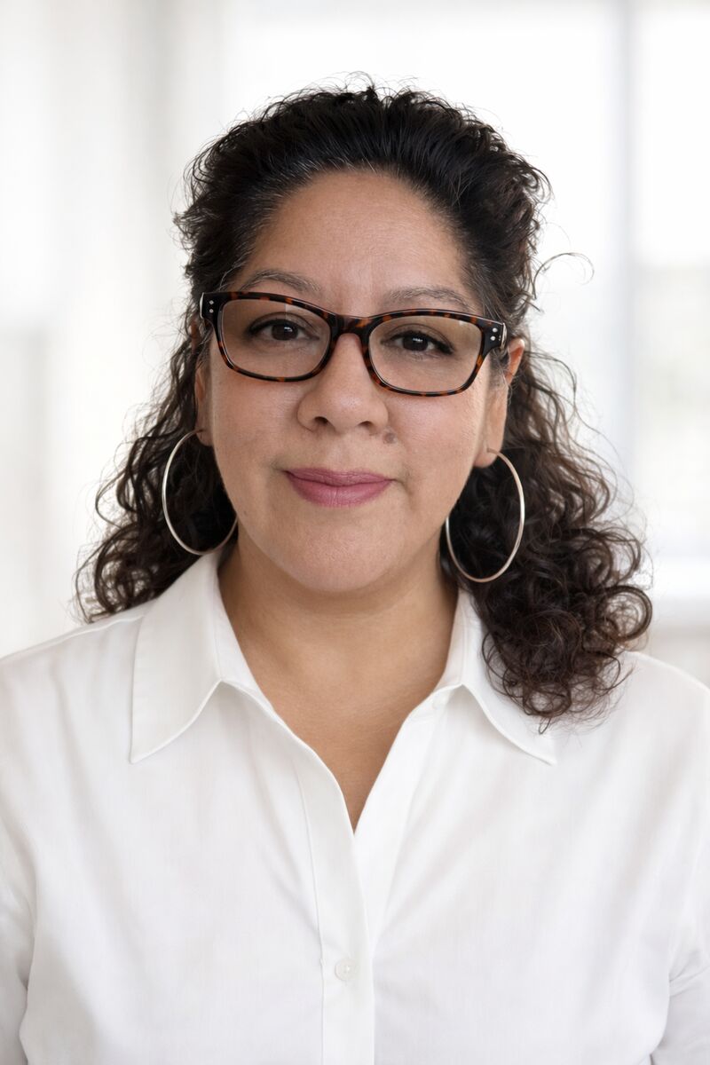 Portrait of Alicia Pierce, smiling, wearing glasses and a white shirt